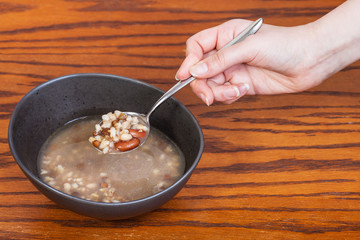 hand holding spoon with beans soup over bowl