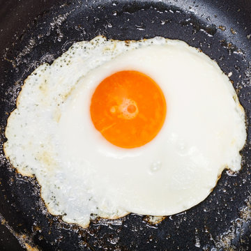 top view of one fried egg in black frypan