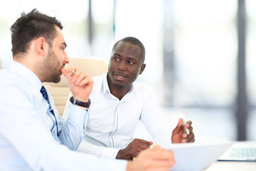 Image of two young businessmen interacting at meeting in office