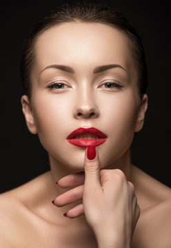 Beautiful Woman with red lips touching her Lips.