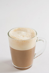 Cappuccino in a transparent cup on the white table