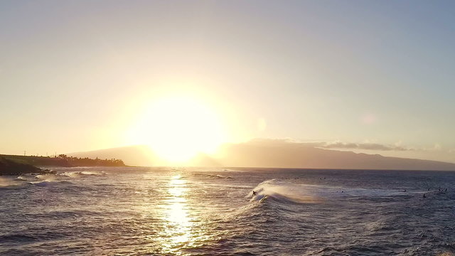 AERIAL Flight Over Surfers Surfing Ocean Waves at Sunset. Amazing Sunset Aerial Shot Flying Low Over Ocean