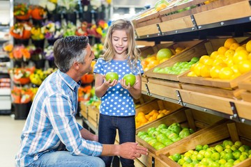 Smiling father giving apples to his cute daughter