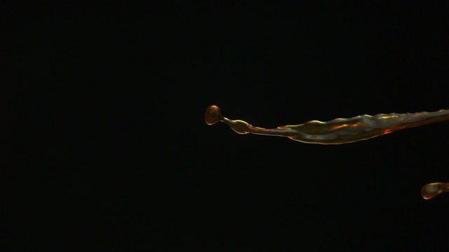 Pouring coffee and making splashes on black background shooting with high speed camera, phantom flex.