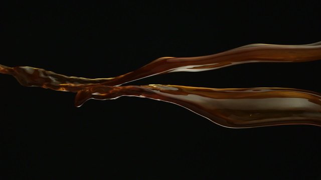 Pouring coffee and making splashes on black background shooting with high speed camera, phantom flex.