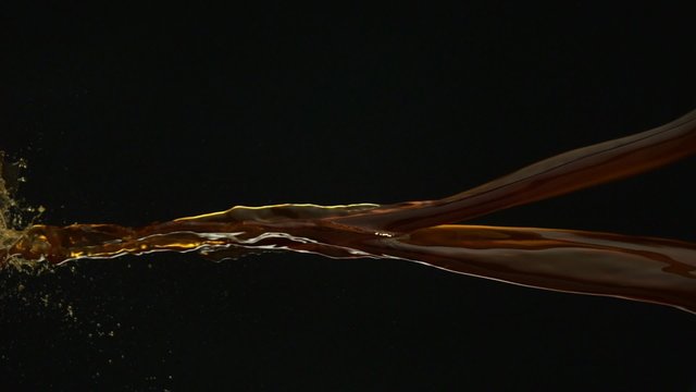 Pouring coffee and making splashes on black background shooting with high speed camera, phantom flex.