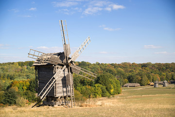 Fototapeta na wymiar Windmill standing on the edge of the autumn forest