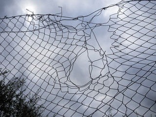 Hole, gap in the wire mesh fence, badly mended.