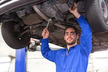 Young attractive mechanic working on a car at the garage