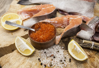 Fresh Norwegian rainbow trout with lemon red caviar, sea salt and onions on a wooden background