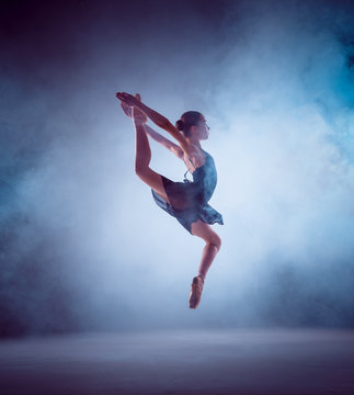 The silhouette of young ballet dancer jumping on a blue background
