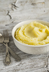 mashed potatoes in a white bowl on a light wooden background