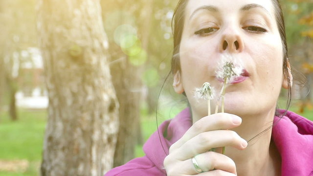 The young woman  blowing dandelion in the park in slow motion, Slow Motion Video clip
