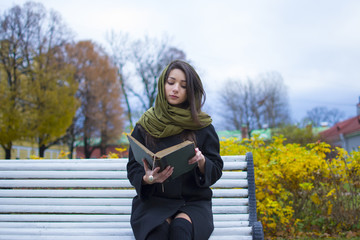 Naklejka na ściany i meble girl sitting on a bench and reading a book