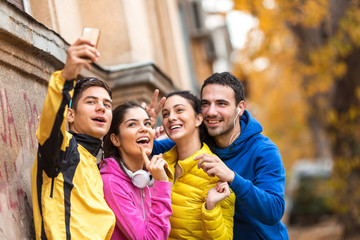 Young friends doing selfie after jogging.They standing against the wall.