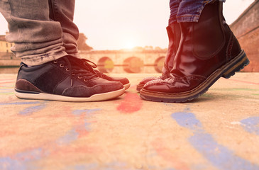 Young couple kissing outdoors - Lovers on a romantic date at sunset,girls stands on tiptoe to kiss her man - Close up on shoes - Love and romantic concept