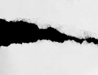 Piece of torn paper on black. Copy space