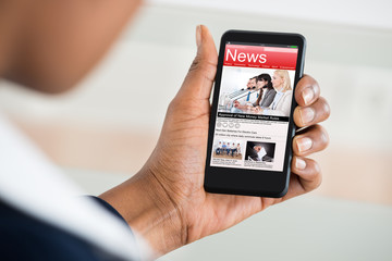 Woman Reading News On Mobile Phone
