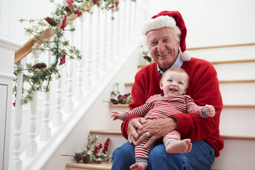 Grandfather With Granddaughter Sits On Stairs At Christmas