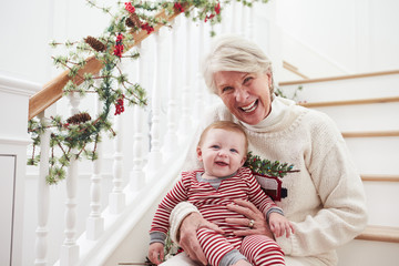 Grandmother With Granddaughter Sits On Stairs At Christmas