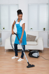 Woman Cleaning Floor With Vacuum Cleaner