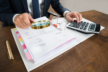 Businessman Checking Invoice With Magnifying Glass