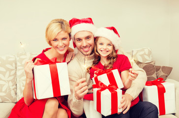 smiling family holding gift boxes and sparkles