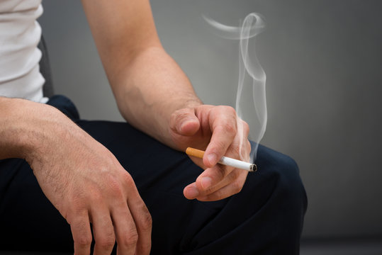 Midsection Of Man Holding Cigarette
