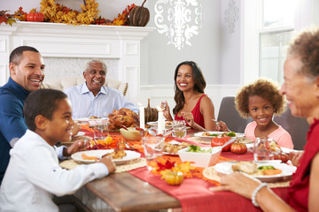 Family With Grandparents Enjoying Thanksgiving Meal At Table - Powered by Adobe