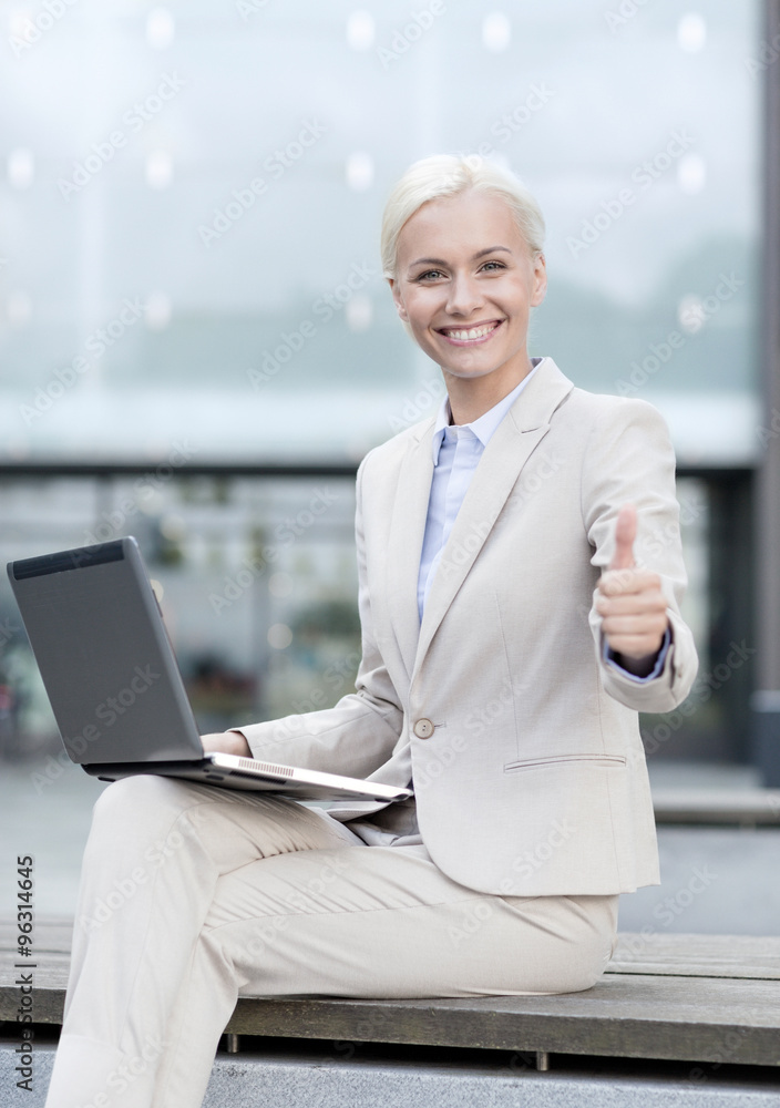 Sticker smiling businesswoman working with laptop outdoors