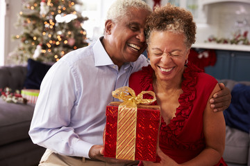 Senior Couple Exchanging Christmas Gifts At Home - Powered by Adobe