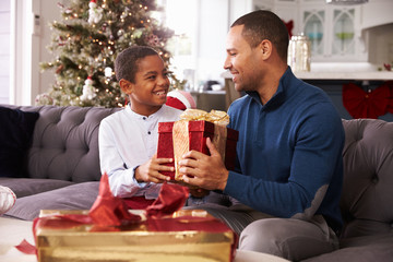 Father And Son Opening Christmas Presents At Home Together