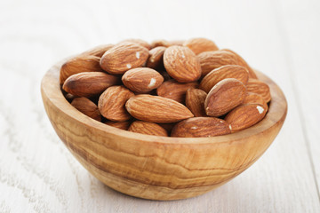 olive bowl full of almonds on wood table