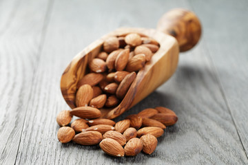 almonds in scoop on gray wooden table