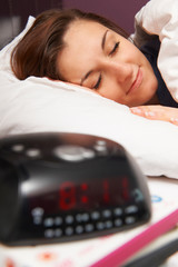 Teenage Girl In Bed Sleeping Through Alarm