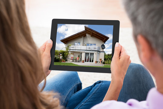 Couple Looking At House Photo On Digital Tablet