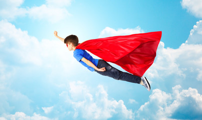 boy in red superhero cape and mask flying on air © Syda Productions
