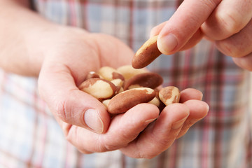 Close Up Of Man Eating Healthy Snack Of Brazil Nuts - obrazy, fototapety, plakaty