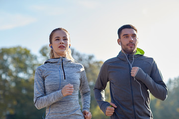 happy couple with earphones running outdoors