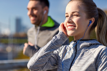 happy couple with earphones running in city