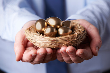 Businessman Holding Nest Full Of Golden Eggs
