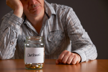 Depressed Man Looking At Empty Jar Labelled Christmas