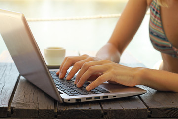 Close up of woman hands using laptop on the beach. Selective focus