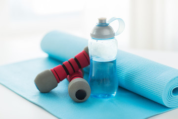 close up of bottle, dumbbells and sports mat