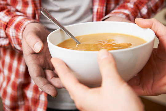 Homeless Man Being Handed Bowl Of Soup By Volunteer