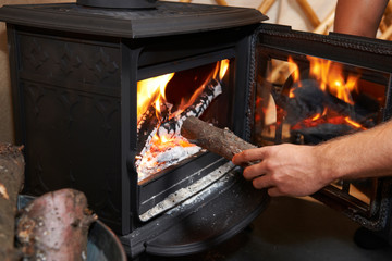 Man Putting Log Onto Wood Burning Stove