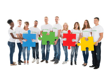 Fototapeta premium Portrait Of Confident Volunteers Holding Jigsaw Pieces