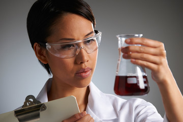 Scientist Holding Clipboard And Examining Beaker