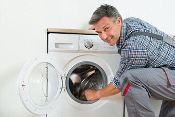 Repairman Checking Washing Machine At Home