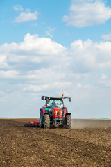 Obraz premium Farmer in tractor preparing land with seedbed cultivator